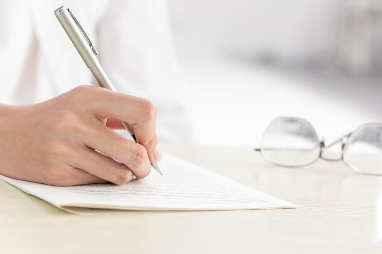 A person writing a cover letter, focusing on tailoring content to the job description and showcasing qualifications, skills, and enthusiasm to make a strong impression.
